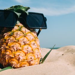 un ananas sur la plage avec des lunettes de soleil, de quoi célébrer l'été au soleil