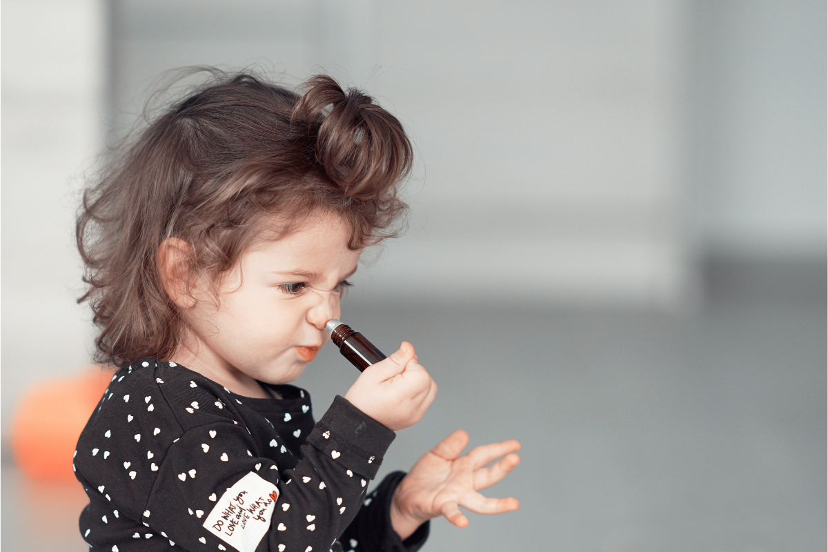 L'image représente une petite fille en train de sentir une huile essentielle