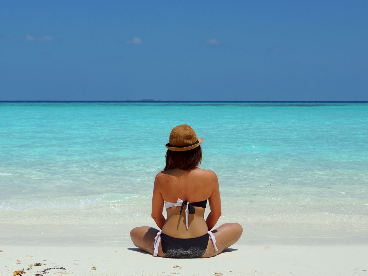 Une femme assise sur la plage qui est en train de prendre un coup de soleil