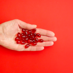 Rode capsules in de ene hand, symbool voor voedingssupplementen om het immuunsysteem te versterken.