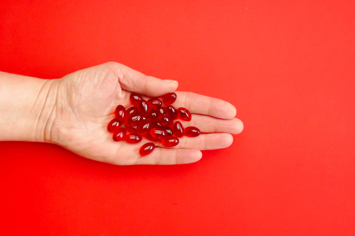 Rode capsules in de ene hand, symbool voor voedingssupplementen om het immuunsysteem te versterken.