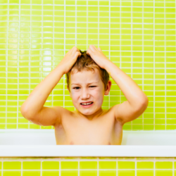 un enfant dans une baignoire qui se gratte la tete. Poux de l'été : les différentes solutions pour les éviter sur la plage