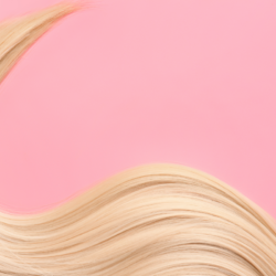 Mèche de cheveux blonds ondulés sur fond rose, symbolisant la santé et la beauté capillaire.