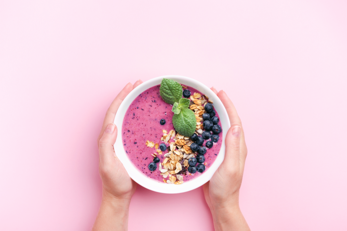 L'image représente un smoothie bowl coloré, avec des fruits, du basilic, du gingembre en poudre, de la farine de coco et différents produits de la marque Écoidées