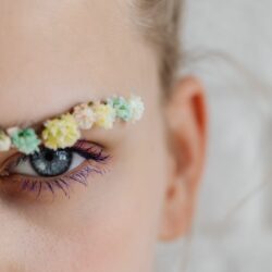 une femme maquillée avec des fleurs dans les sourcils