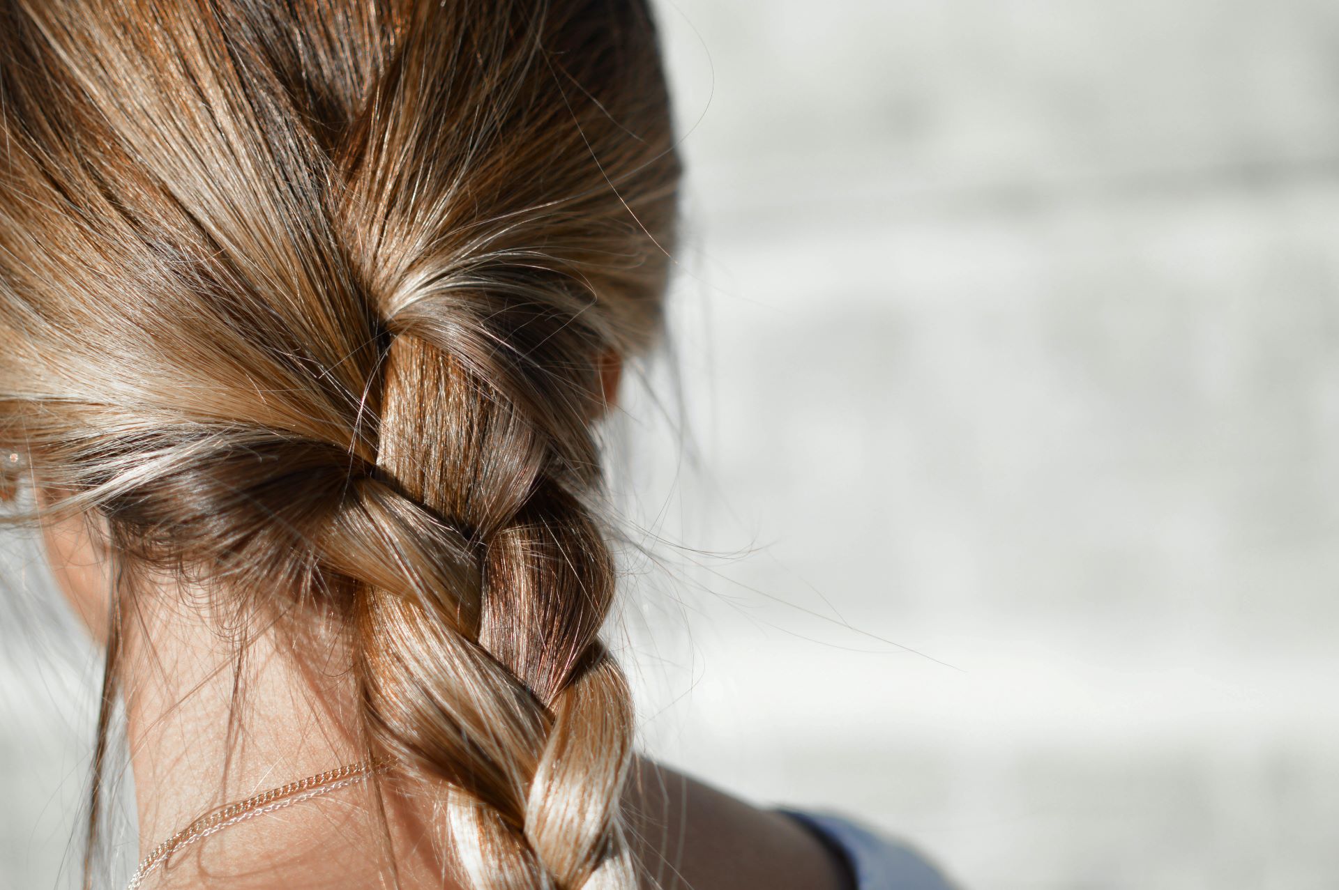 l'image représente une femme aux cheveux longs noués avec une tresse. été reflets cheveux