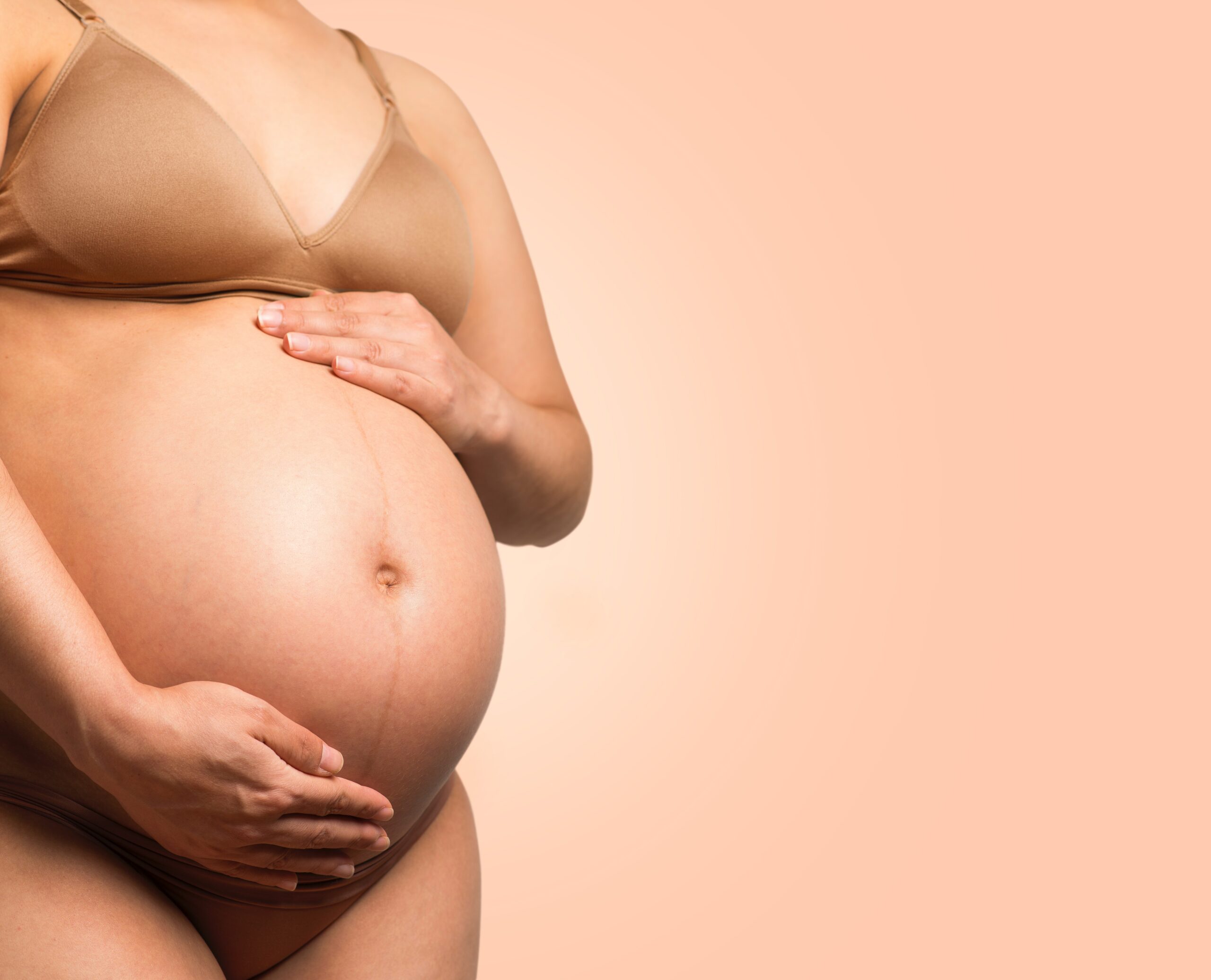 enceinte. L'image représente le corps d'une femme enceinte. Elle pose ses deux mains sur son ventre. Profitez pleinement de votre grossesse cet été grâce à nos conseils pour rester fraîche et confortable malgré la chaleur.