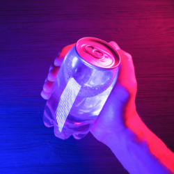 Une main tenant une canette transparente éclairée par des lumières néon roses et bleues, créant une ambiance futuriste et vibrante sur une surface en bois sombre. Quels sont les bienfaits du maté ?
