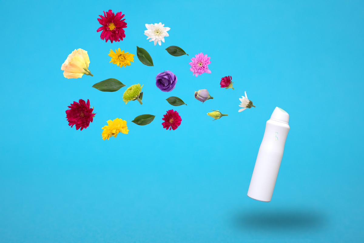 Une bouteille de spray blanc avec le logo en vert est positionnée à droite sur un fond bleu clair. À gauche, un assortiment de fleurs colorées en lévitation, incluant des dahlias rouges, des chrysanthèmes jaunes, des roses, et des fleurs de passiflore, symbolisant les ingrédients naturels utilisés dans le spray.