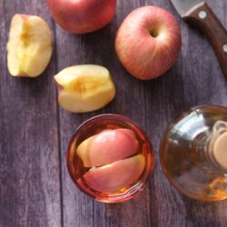pomme avec un couteau et du vinaigre de cidre sur une table en bois