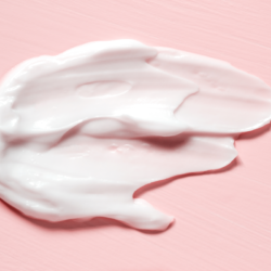L'image représente de la crème étalée sur un fond rose. Hydrocrème Mon Hydratant Visage pour Peau Atopique Pas Cher Sans Parfum et Disponible en Pharmacie