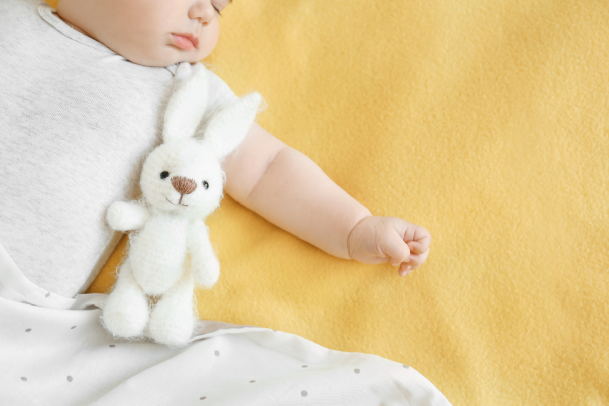 Découvrez les avantages et inconvénients de l'homéopathie pour les bébés. Une analyse complète des traitements naturels spécifiques pour les tout-petits, avec un regard sur l'efficacité et les précautions nécessaires. L'image représente un bébé endormi sur un drap jaune, avec un doudou lapin.