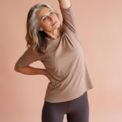 Femme d’environ 50 ans effectuant un étirement latéral doux pour soulager les raideurs musculaires et articulaires liées à la ménopause, sur fond neutre et apaisant.