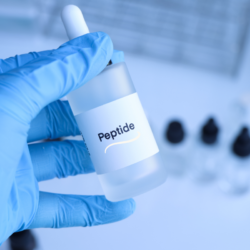 Flacon de peptide BPC-157 tenu par une main gantée en laboratoire, représentant les applications thérapeutiques du peptide BPC-157.