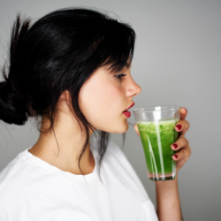 Woman drinking an antioxidant-rich green smoothie for the natural detoxification of heavy metals such as lead and cadmium, promoting the elimination of toxins thanks to natural dietary solutions and detoxifying foods such as spirulina and coriander.