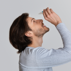 Homme appliquant des gouttes ophtalmiques pour soulager la sécheresse oculaire. Illustration de l'utilisation des larmes artificielles, traitement courant des symptômes tels que l'irritation, la rougeur et la sensation de brûlure. Solution idéale pour stabiliser le film lacrymal, améliorer l’hydratation et réduire l’inflammation oculaire liée aux yeux secs.