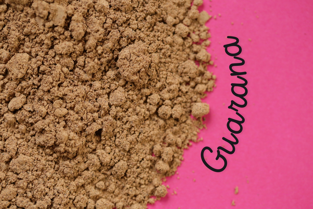 Guarana powder on a pink background, used for its stimulating and energizing properties in herbal medicine.