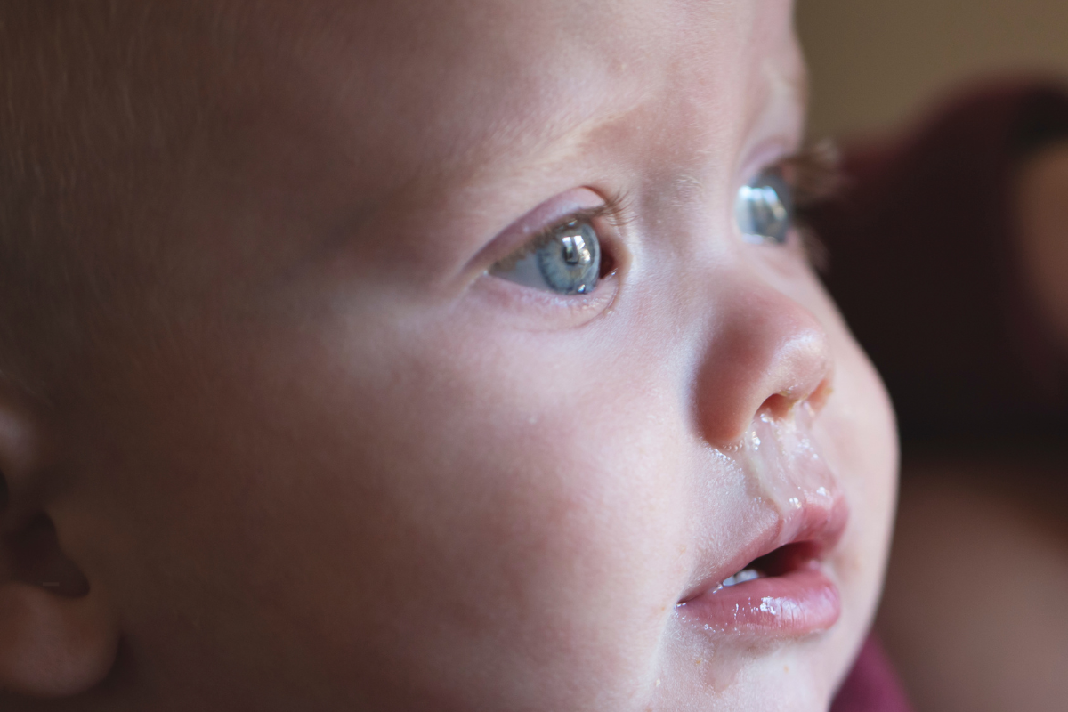 Gros plan sur le visage d’un bébé enrhumé avec un écoulement nasal, illustrant les symptômes du rhume chez le nourrisson