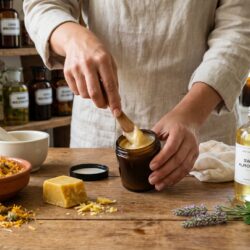 Préparation galénique d'un onguent au calendula pour le soin de la peau avec cire d'abeille et huile d'amande douce sur un établi en bois.
